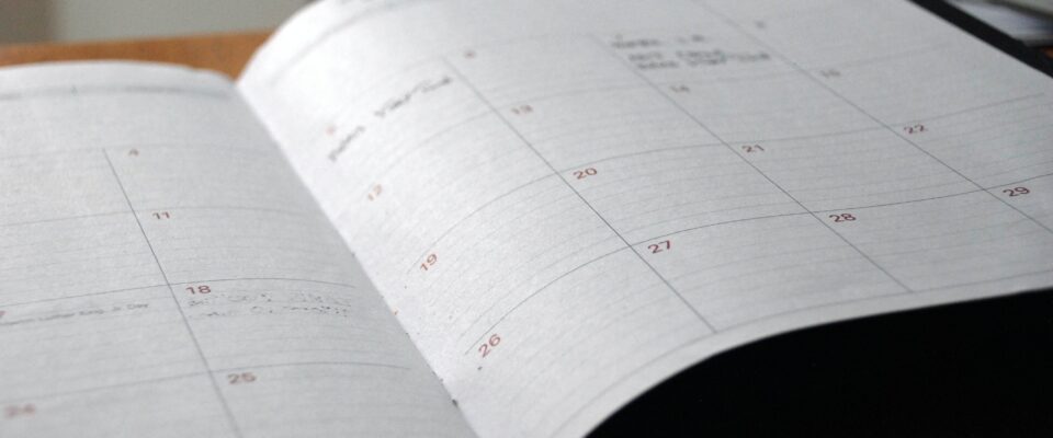 Kalender mit monatlicher Übersicht liegt aufgeklappt auf einem Tisch